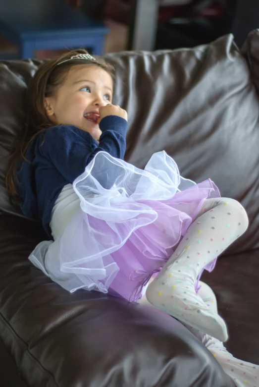 a child sits on the couch and wears a skirt and socks