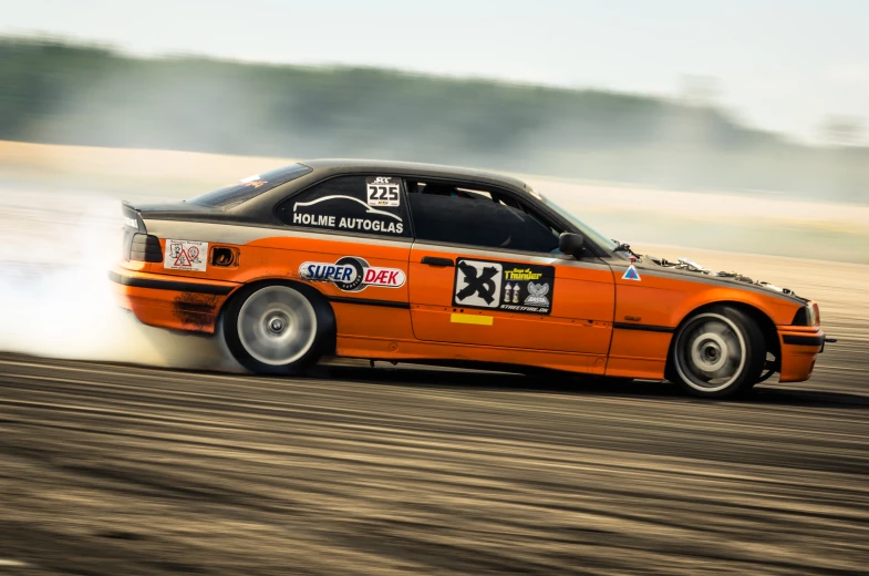 an orange car with a black emblem going down the track