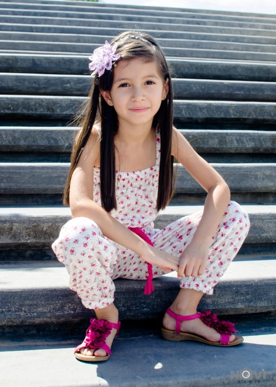 a small girl sitting on some stairs with her hands in her pockets