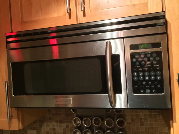 a microwave oven with two electronic controls next to brown cabinets