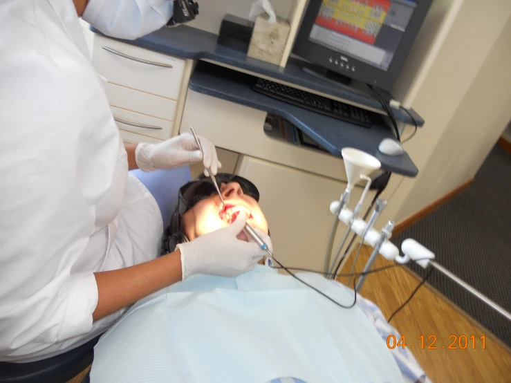 a woman lying in a chair getting teeth checked up by a dentist