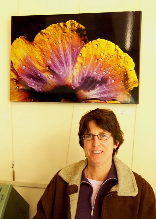 a woman smiling and sitting under a large painting