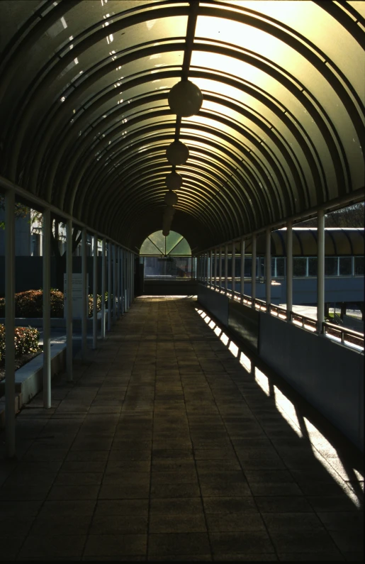 a dark tunnel is under a light with long benches