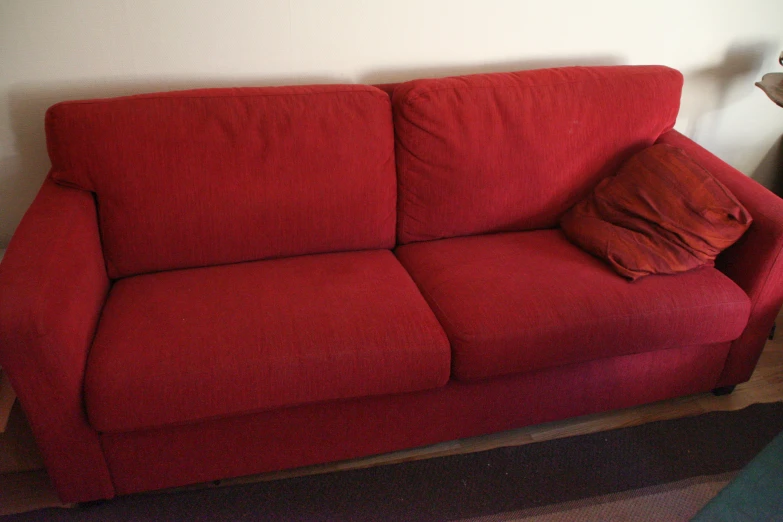 a red couch with two pillows sitting in front of it