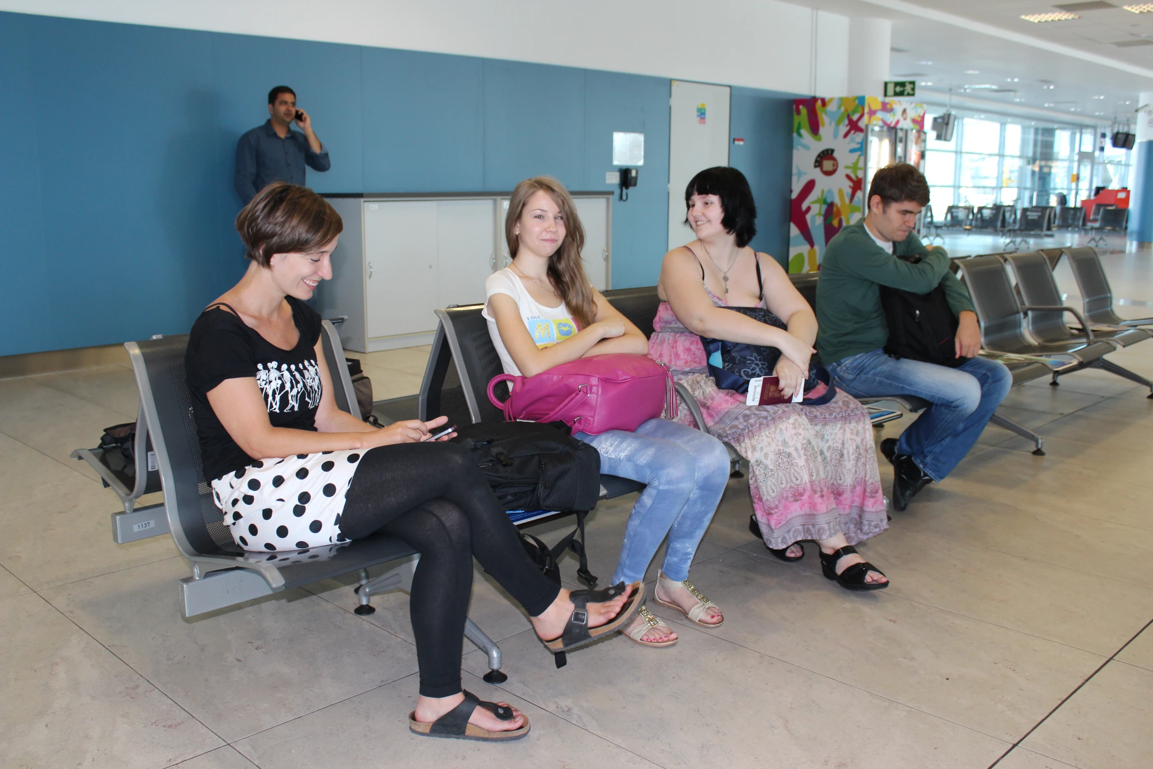 four women sitting next to each other waiting for their luggage