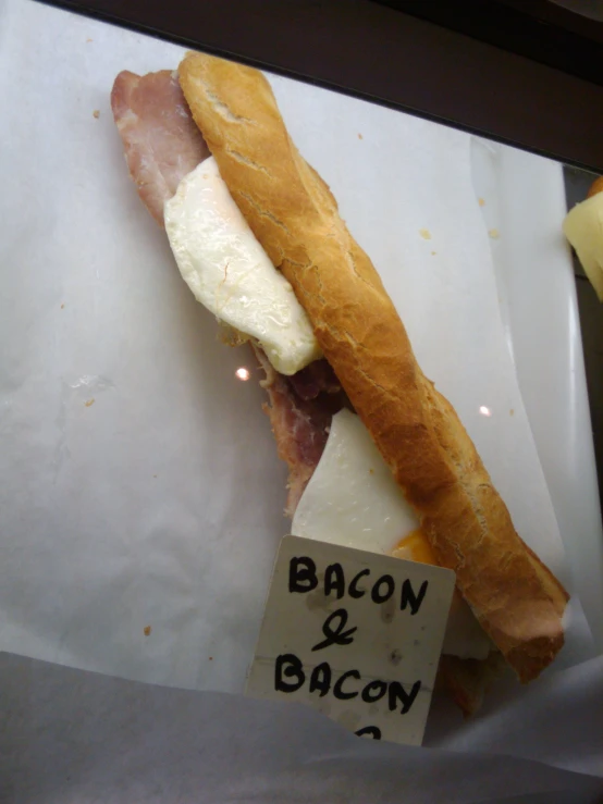 a sandwich with bacon and cheese sitting on paper