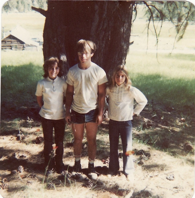 four children pose next to a tree at the park