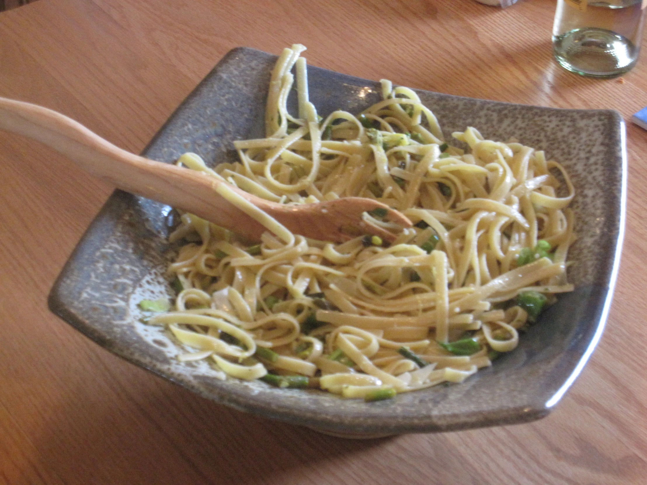 spaghetti is in a bowl with a wooden spoon