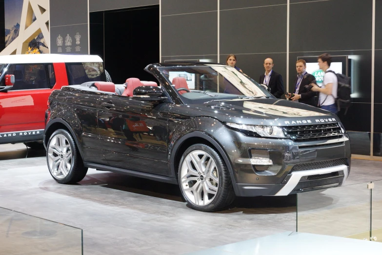 the red, white, and black range rover sits near other vehicles