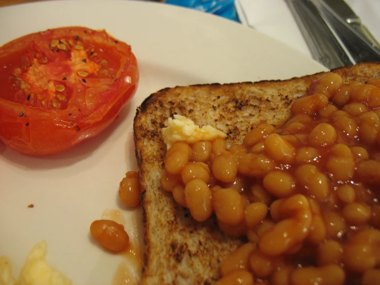 a plate of food with a tomato and baked beans