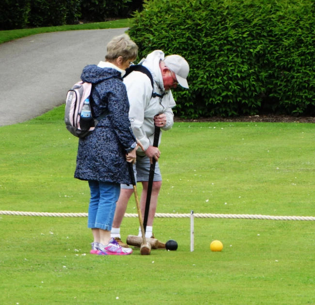 two people are playing croquet on a field