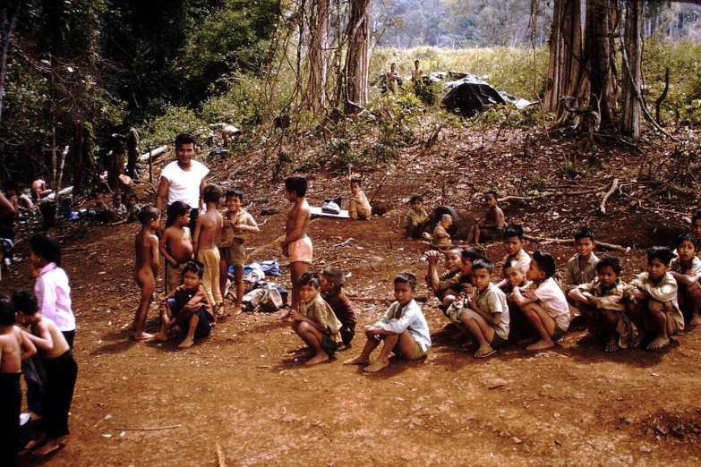 the boys sit in the woods, a lot of children stand by them