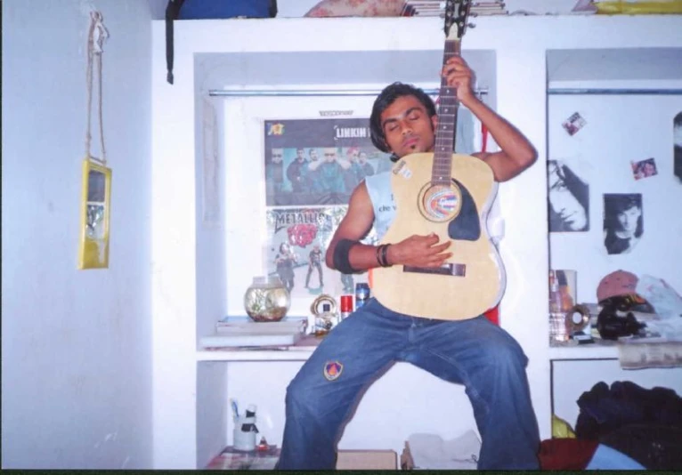 a young man holding up a guitar in his living room