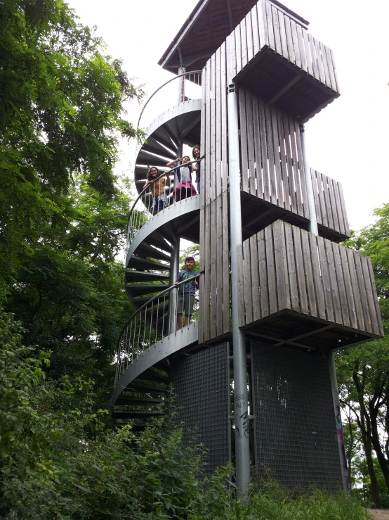 two people are standing on a wooden structure that has spiral stairs