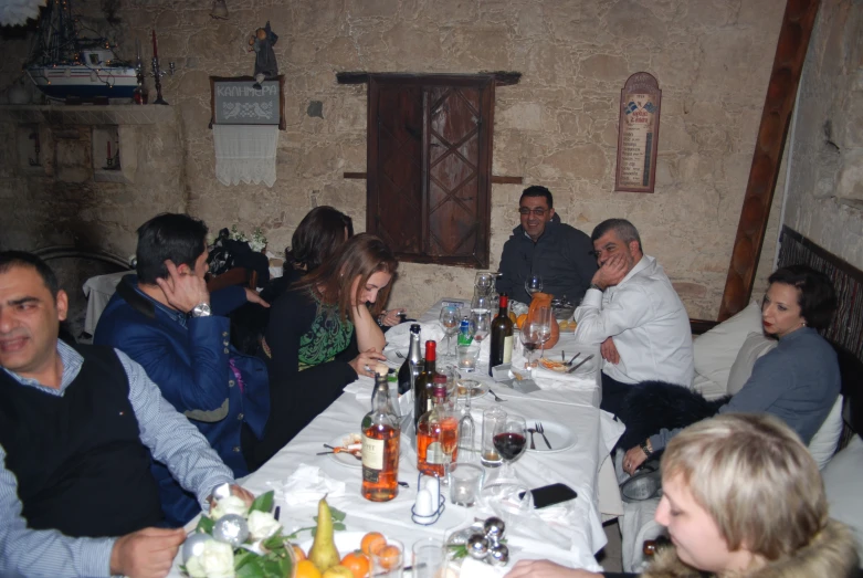 a group of people sitting at a table with bottles