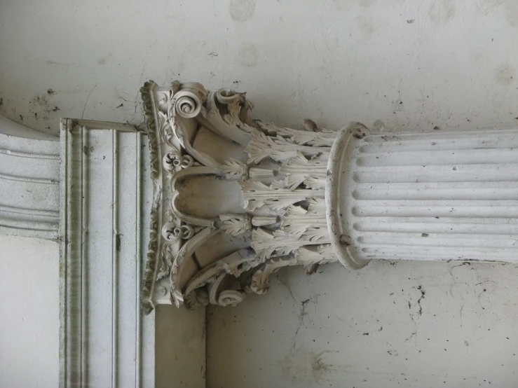 a large column sitting outside of a white building