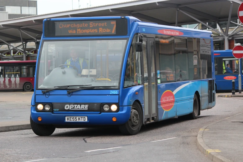 a blue city bus stops at a bus stop