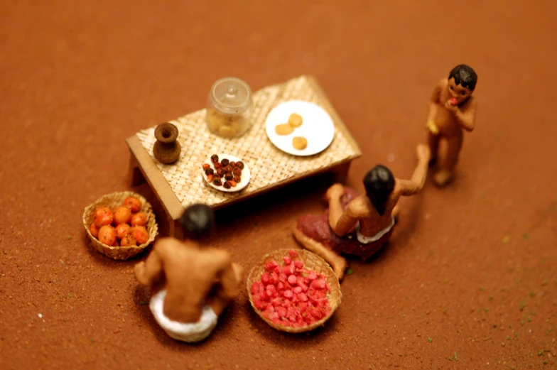 miniature people standing by a table filled with fruit and food