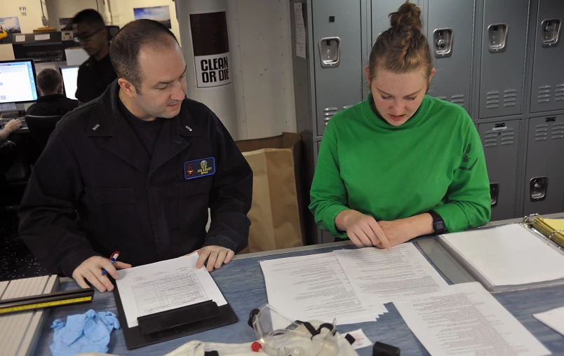 a man and woman sitting at a table doing paperwork