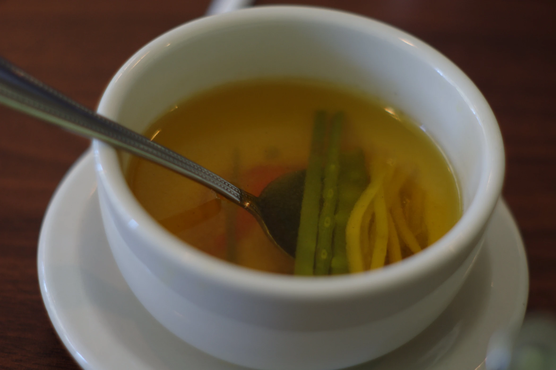 a small white bowl of soup is on a wooden table