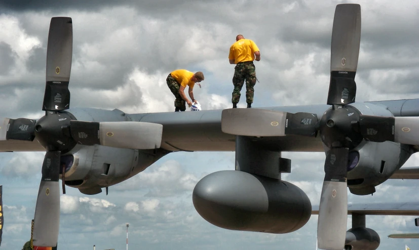 two people are putting paint on the sides of a fighter jet