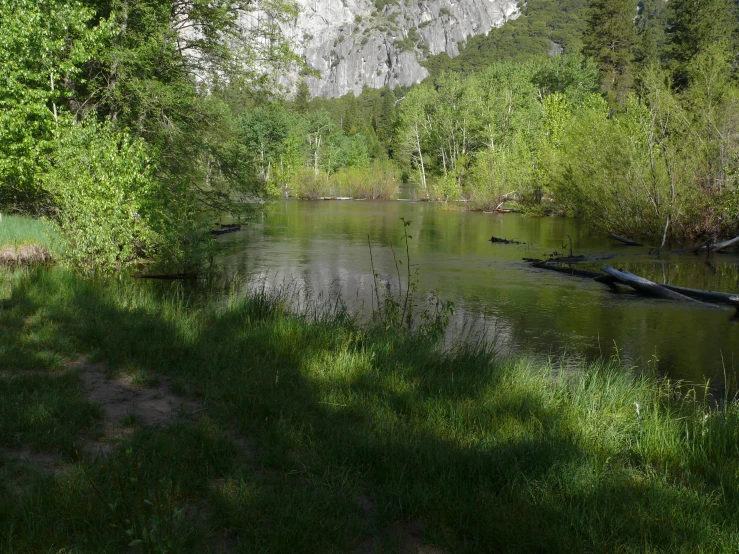 there is a pond surrounded by mountains with green grass