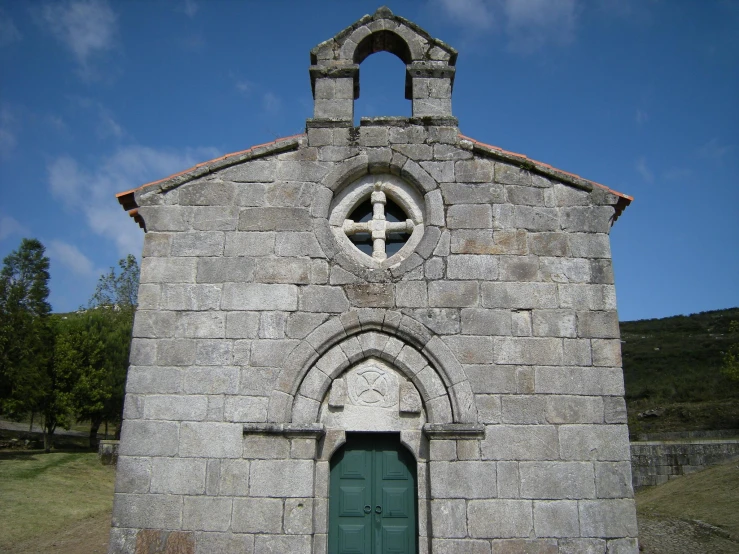 a brick wall with a green door near a cross