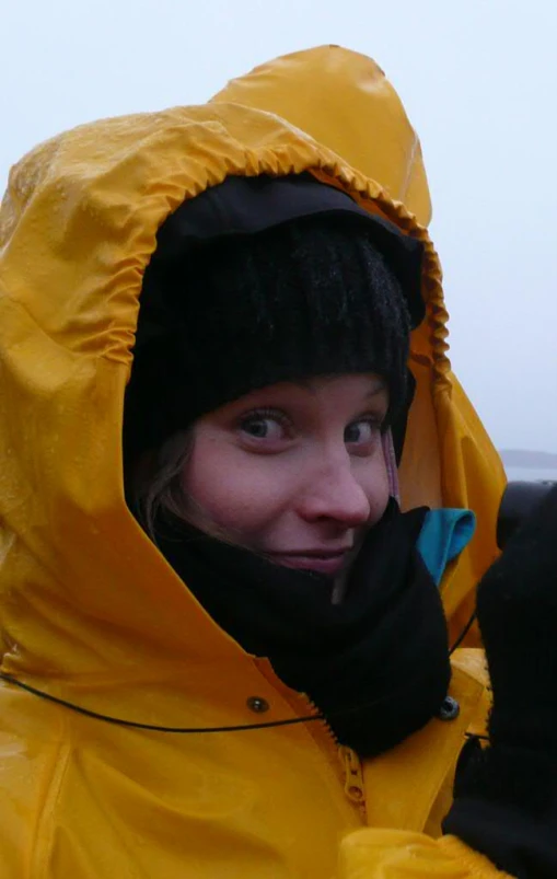 a woman in a yellow parka holding a cell phone to her ear