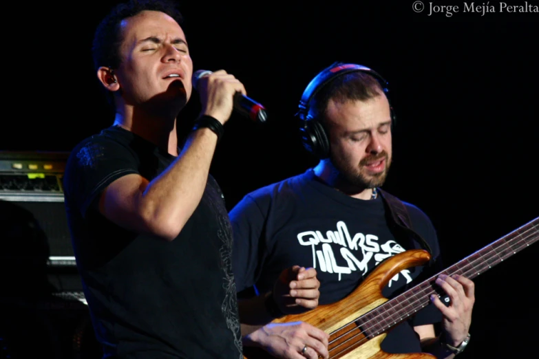 two people with headphones and guitar on stage