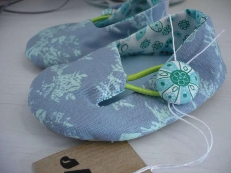 a blue and white floral pair of shoes is being held in a white string