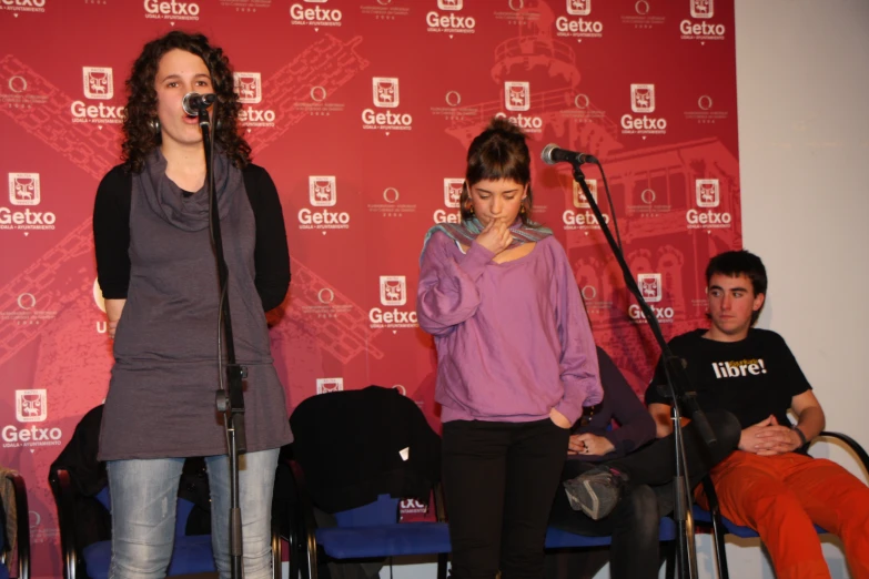 two women standing next to each other on stage