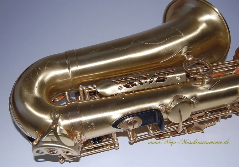 two gold - plated and black alto saxophone pieces on blue surface