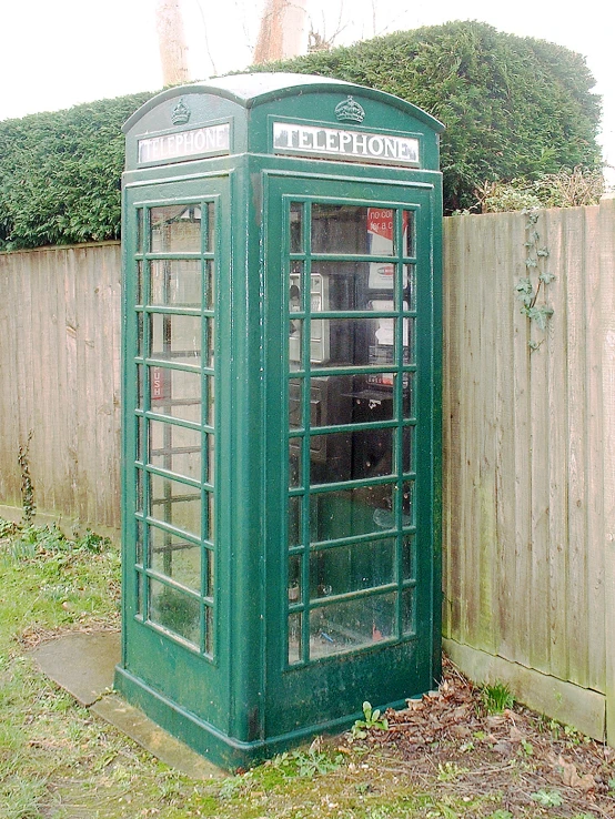 an old style green phone booth in a grassy area