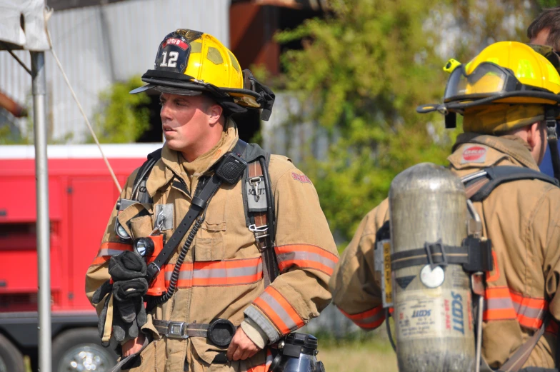 two firefighter standing next to each other near a house