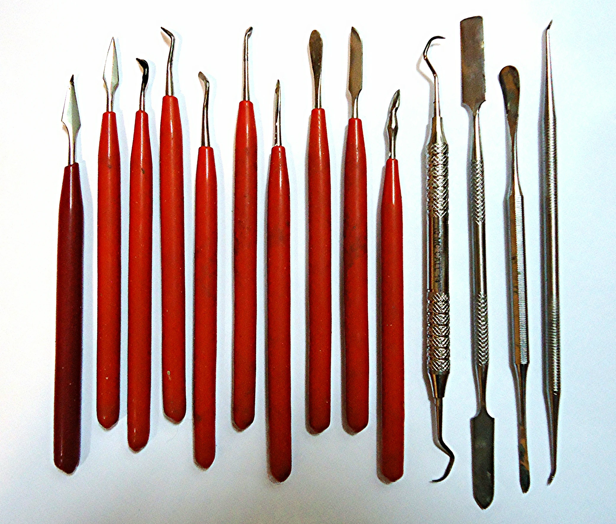 seven different tools, one with the end shaped like arrows, are lined up next to each other on a surface