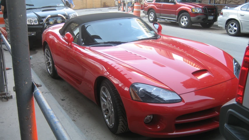 a red sports car parked on the street near other vehicles