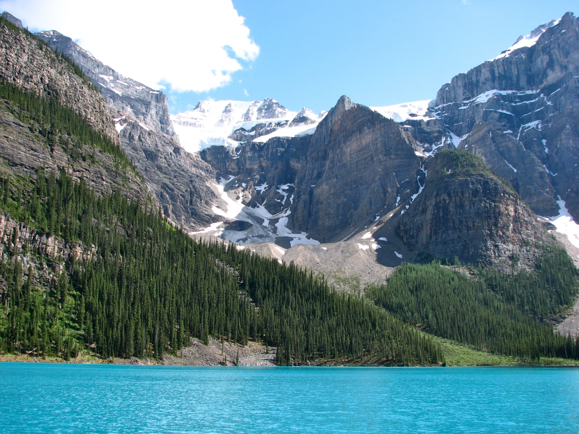 a large mountain with lots of snow sitting above a blue lake