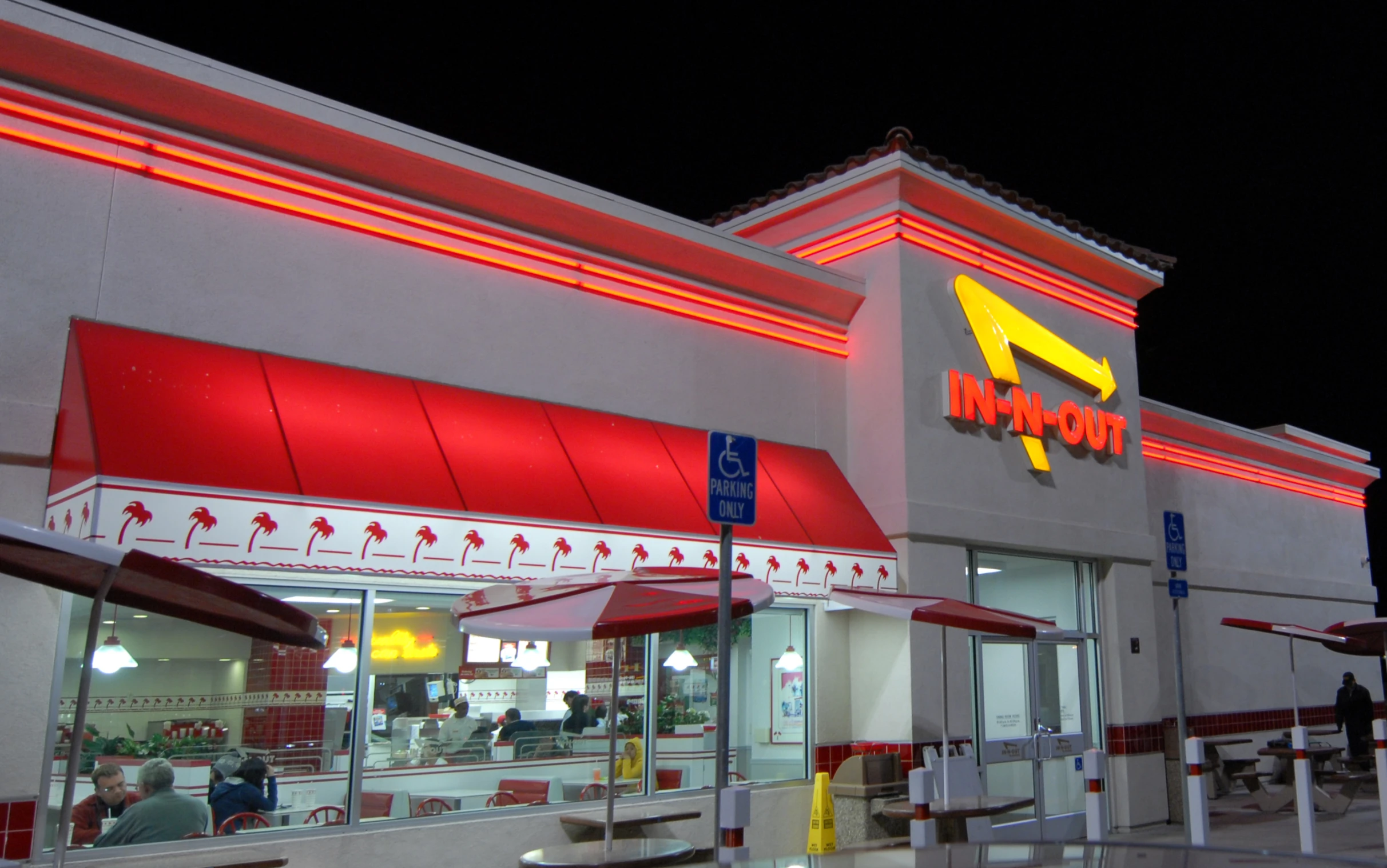 a fast food restaurant with neon lights reflecting in the windows