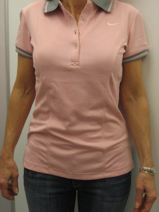 a woman standing in front of a mirror in a pink shirt and blue jeans