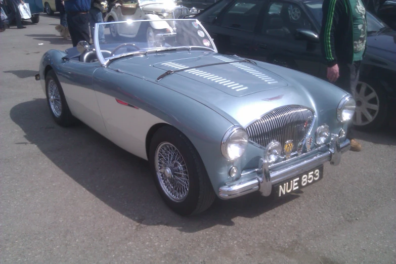 a vintage blue and white car parked near other cars