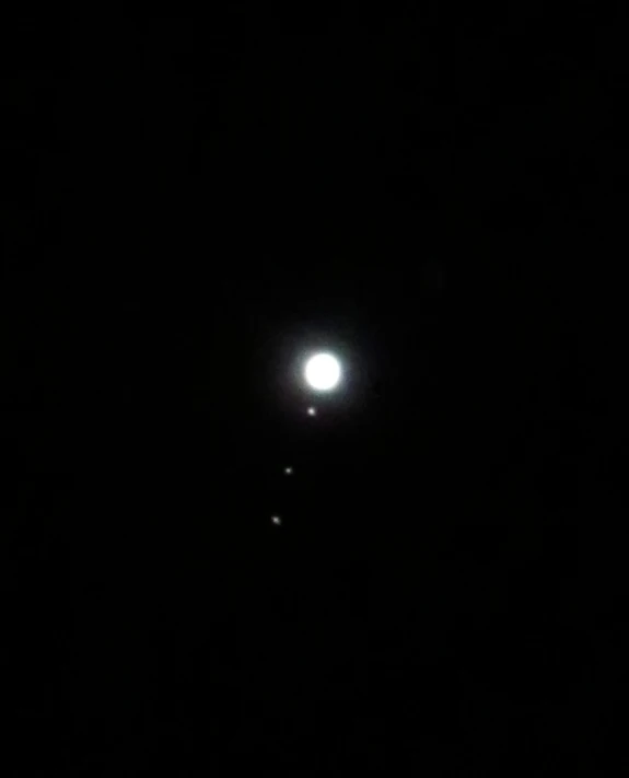 the moon and three stars are lit up in the dark sky