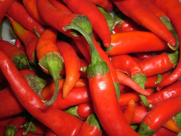 a pile of long  peppers sitting next to each other