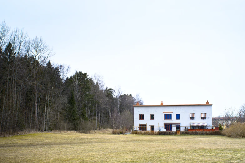 a house sitting in a grass field next to a forest