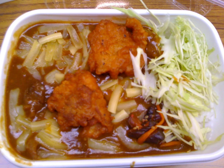 a bowl filled with food and meat on top of a wooden table