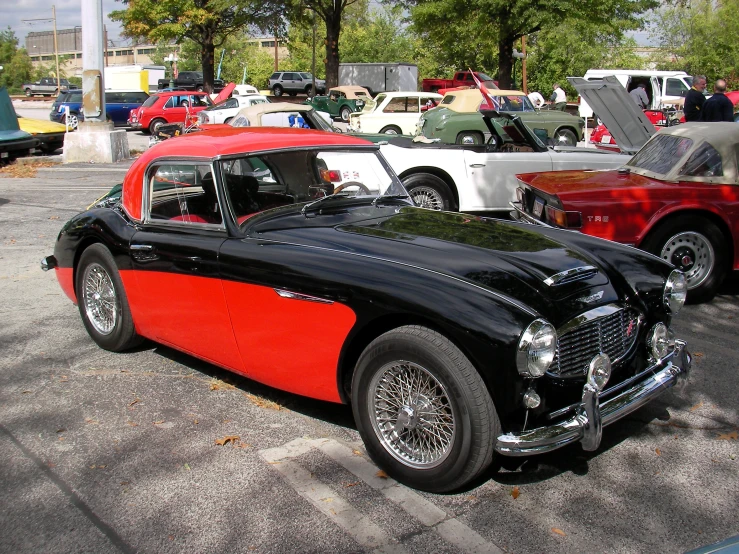 two old fashion sports cars parked next to each other in a parking lot