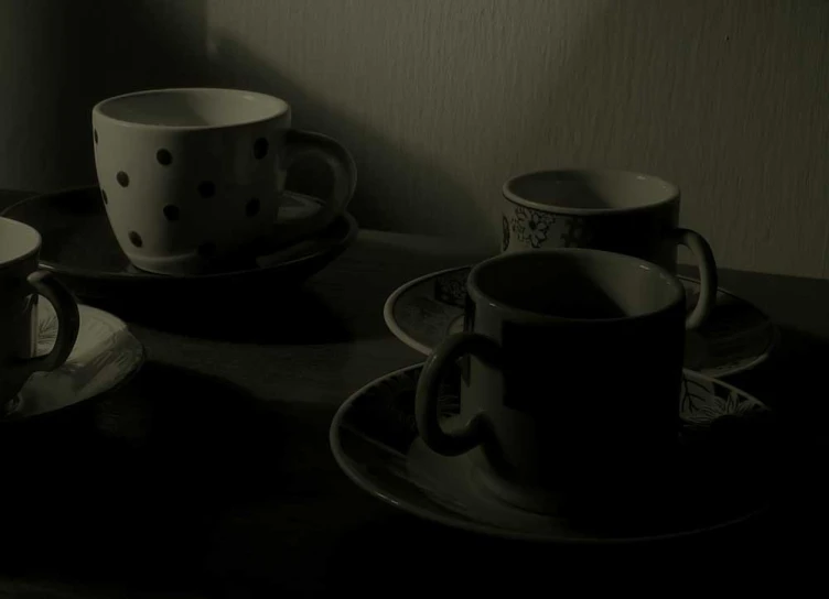 black and white pograph of cups and saucers with one candle