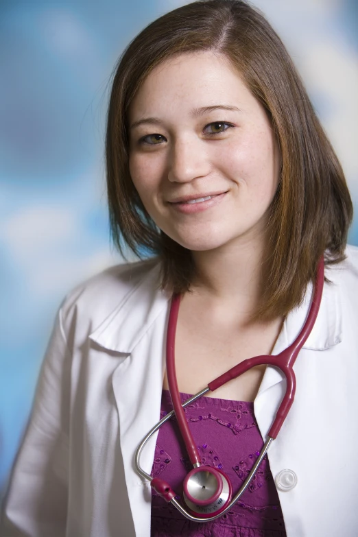 a smiling female nurse in white coat and purple top