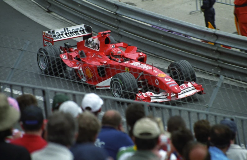 a ferrari car racing down the track, with a large group of people watching