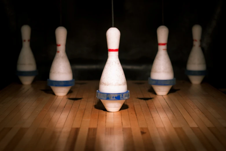 a number of white bowling pins on a wooden floor