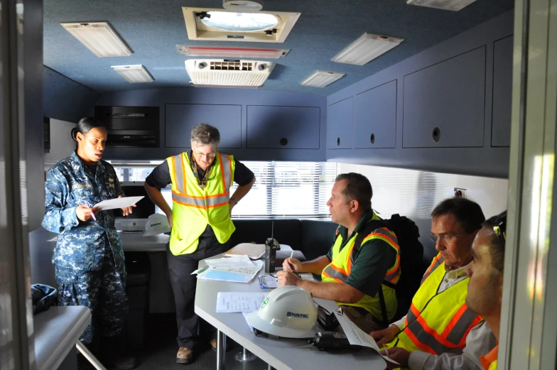 a group of people dressed in reflective vests, standing in a room